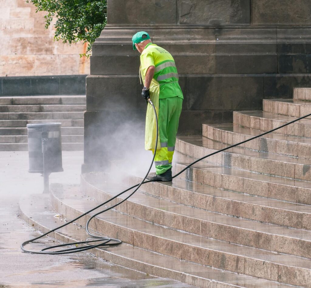 pexels-photo-14965464 A street worker pressure washes stone stairs in a public park, ensuring cleanliness and safety.